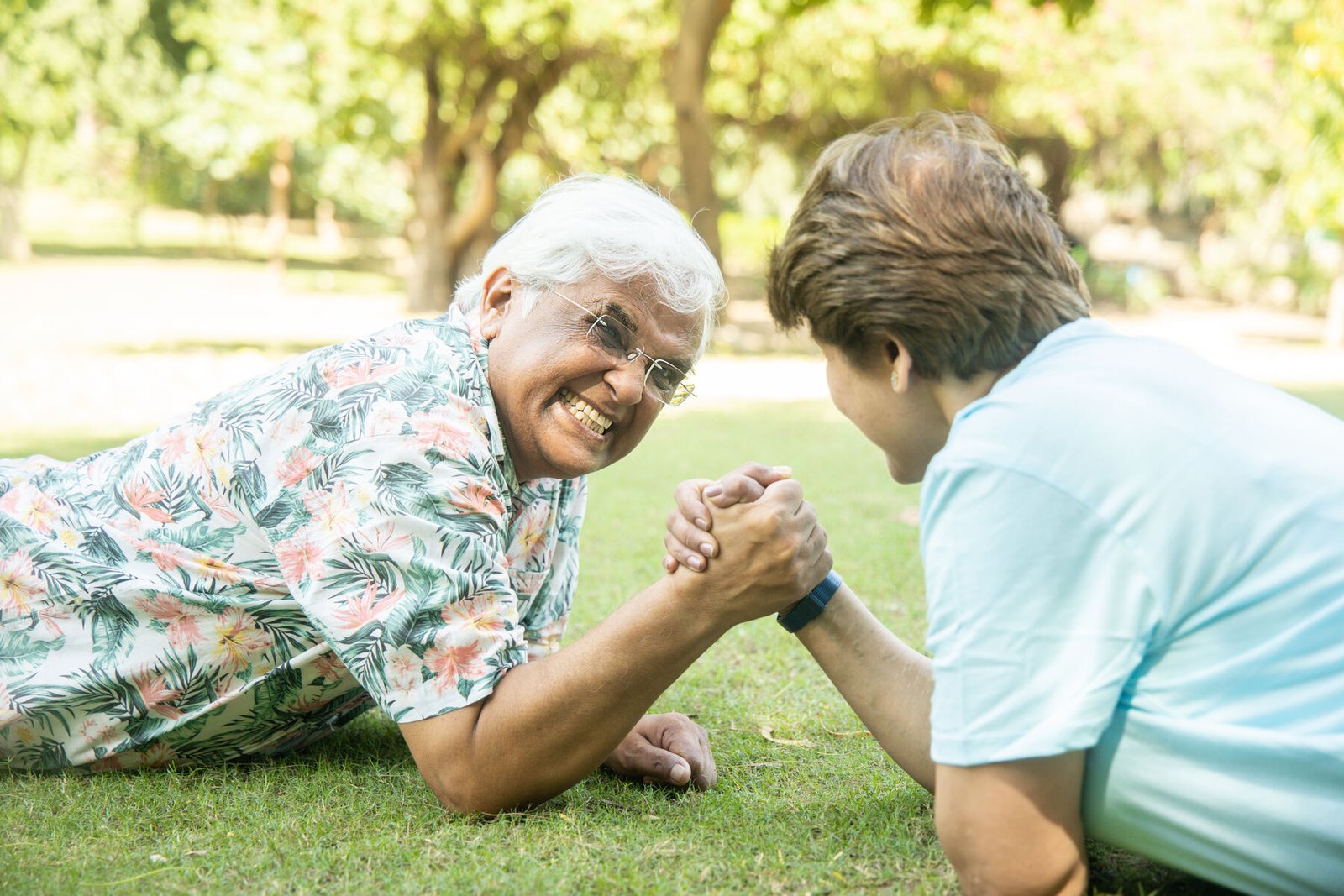 Playful senior couple arm wrestling outdoors